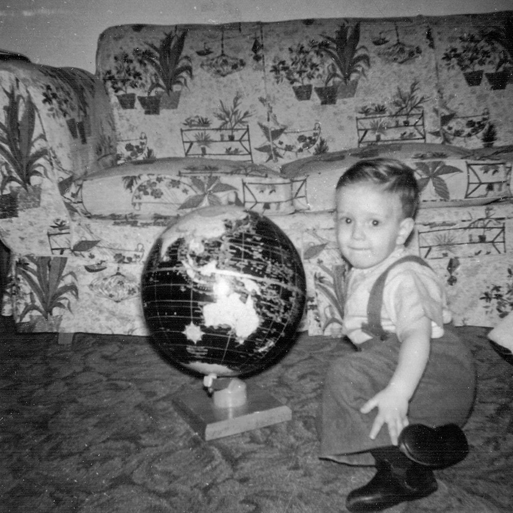 Photograph of me in early 1959 at two years old. I'm sitting on a carpet next to a globe.
