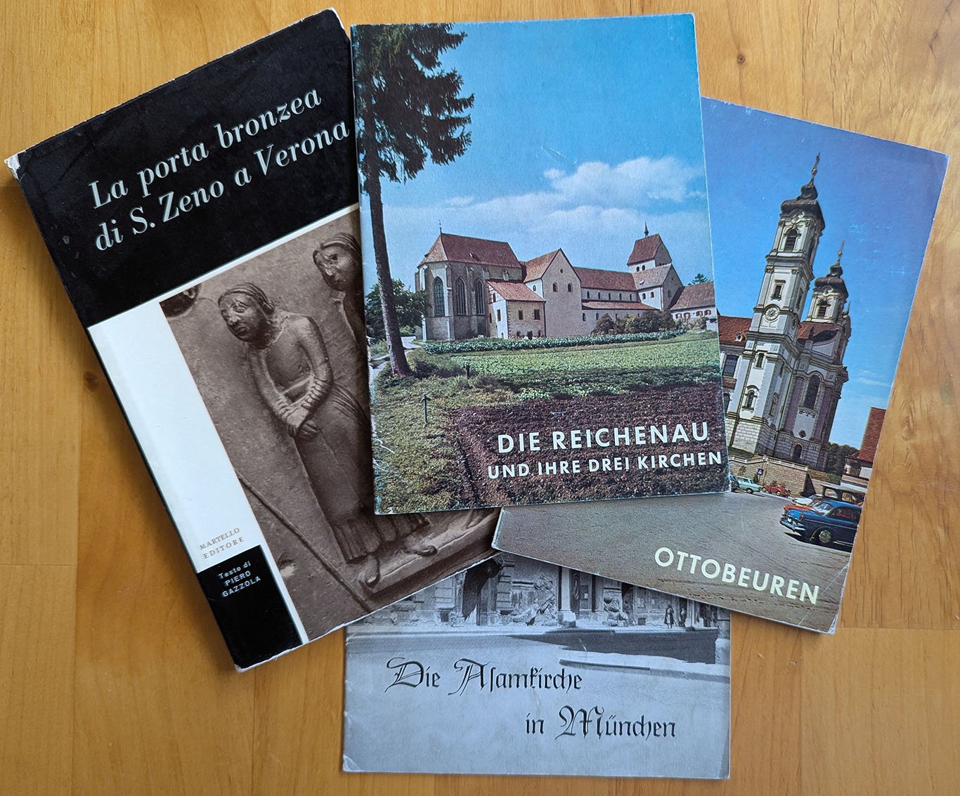Four booklets from my Regis in Austria trip include one in Italian on the bronze doors of San Zeno, Verona; and three others in German on the three churches of Reichenau, the abbey at Ottobeuren, and, titled in an old-fashioned Gothic script, the Asamkirche in Munich. Each has a photograph of the monument on the cover.