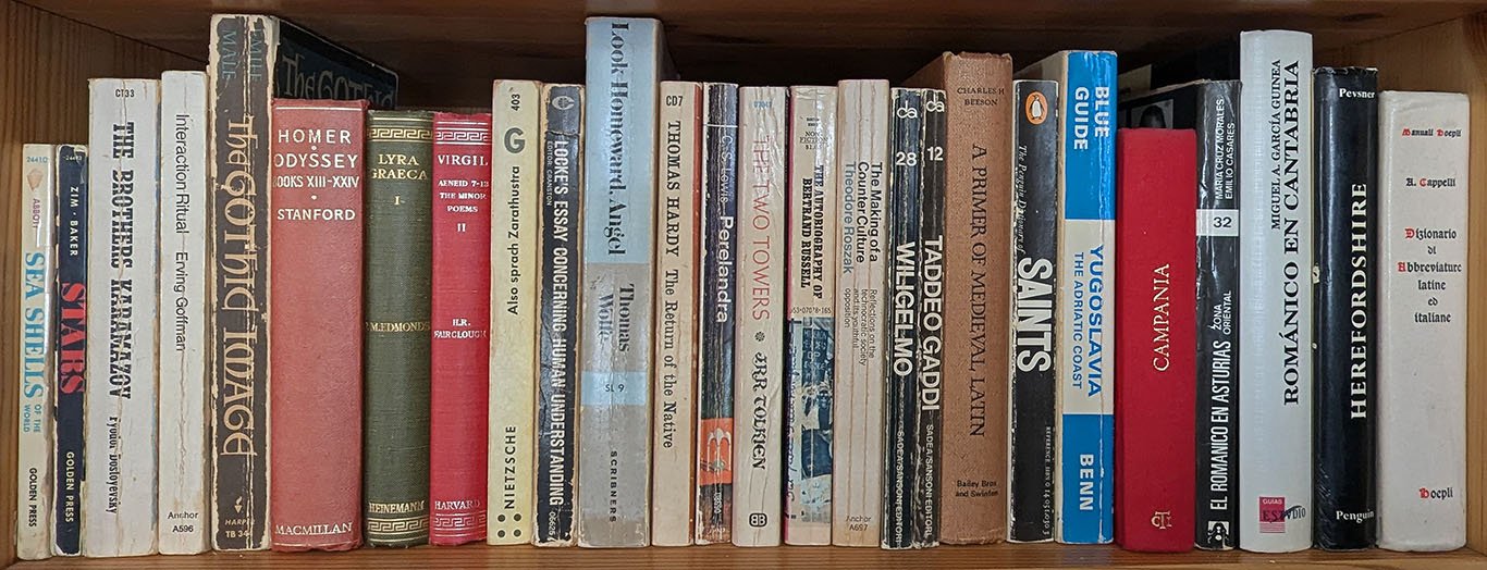 Bookshelf with 26 books, many of them mentioned in this biography. They include Golden Nature guides, novels like The Brothers Karamazov and Look Homeward, Angel; editions of Latin and Greek texts; pocket-sized handbooks of the works of Italian artists Wiligelmo and Taddeo Gaddi; and guidebooks or architectural guides to regions of Yugoslavia, Italy, Spain, and England.